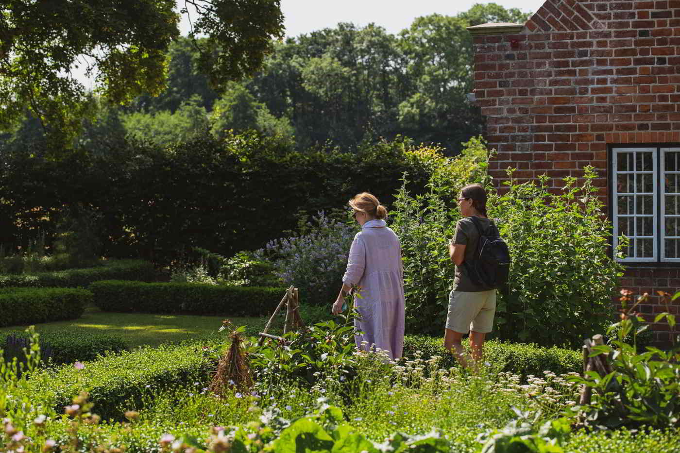 Zwei Frauen gehen durch den Kräutergarten und betrachten die Heilkräuter des Mittelalters im Esrum Kloster.