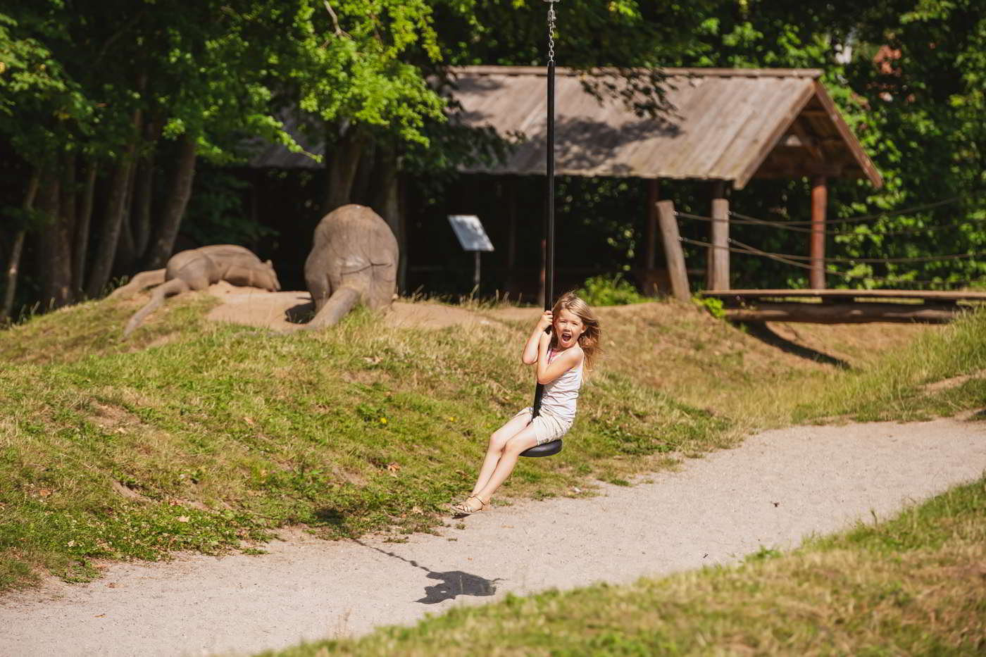 Ein Mädchen lacht, während sie auf der Seilrutsche auf dem Natur-Spielplatz des Esrum Klosters davonfliegt.