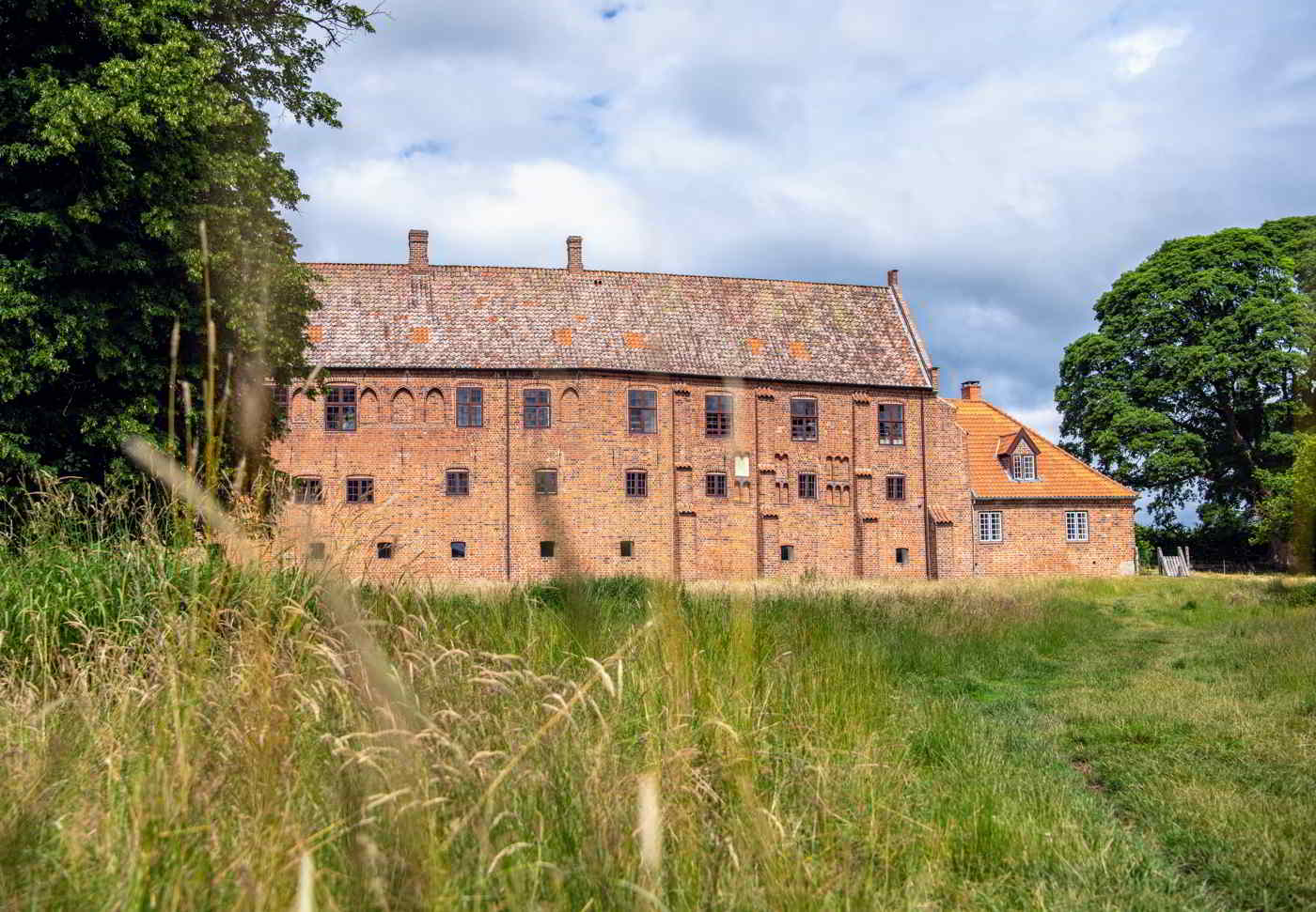 Das rote Ziegelgebäude des Esrum Klosters liegt am Ende einer großen Wiese.