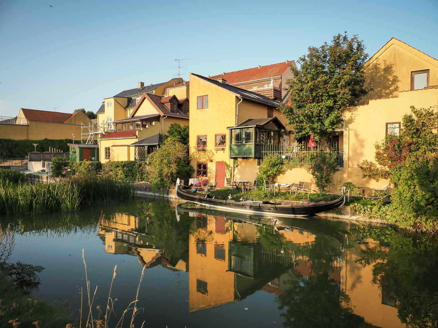 Cozy, yellow buildings bask in the sun on the other side of the canal in Frederiksværk.
