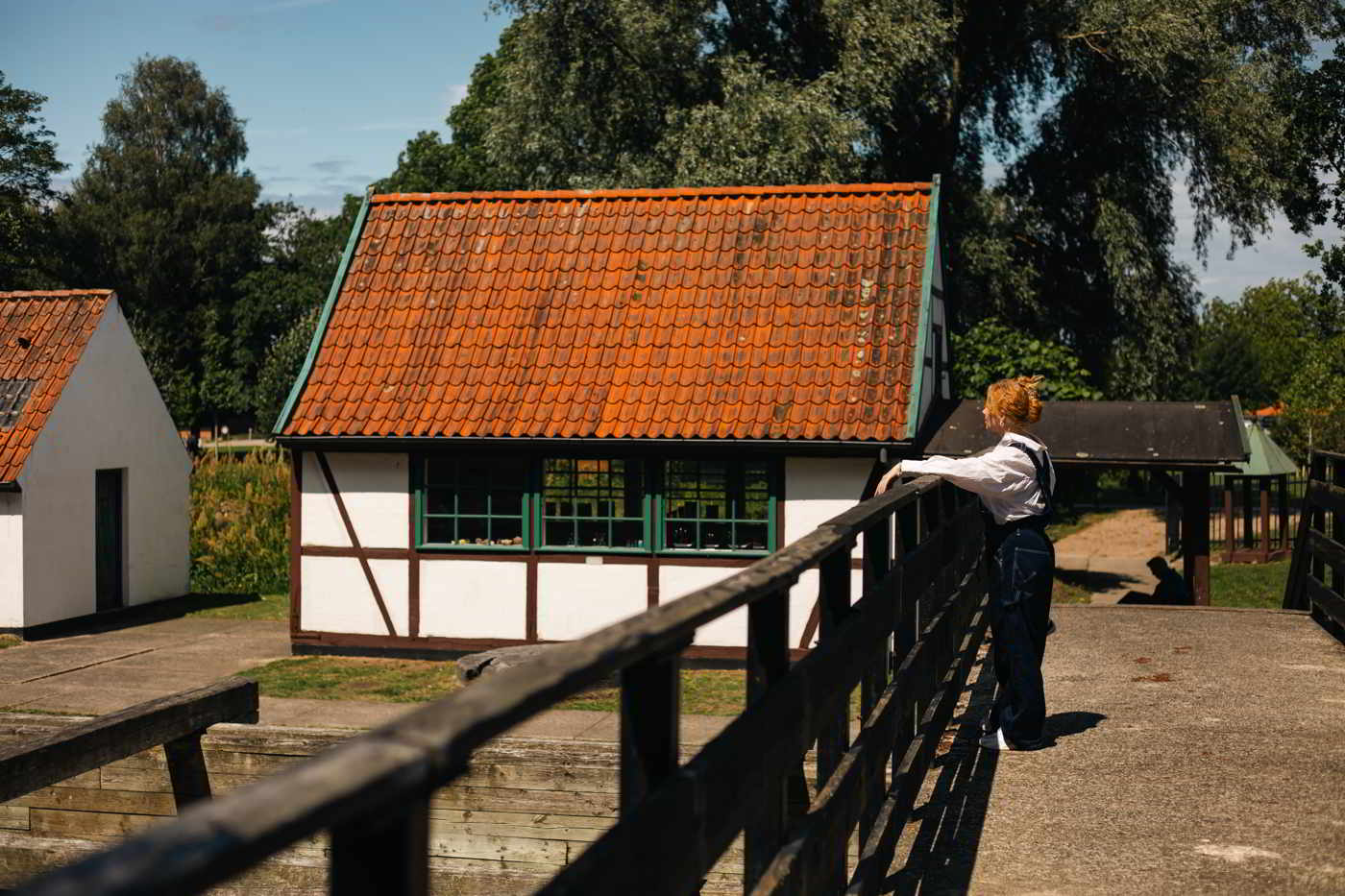 A young woman stands on a bridge and looks at a small half-timbered house in the Gunpowder Works Museum.