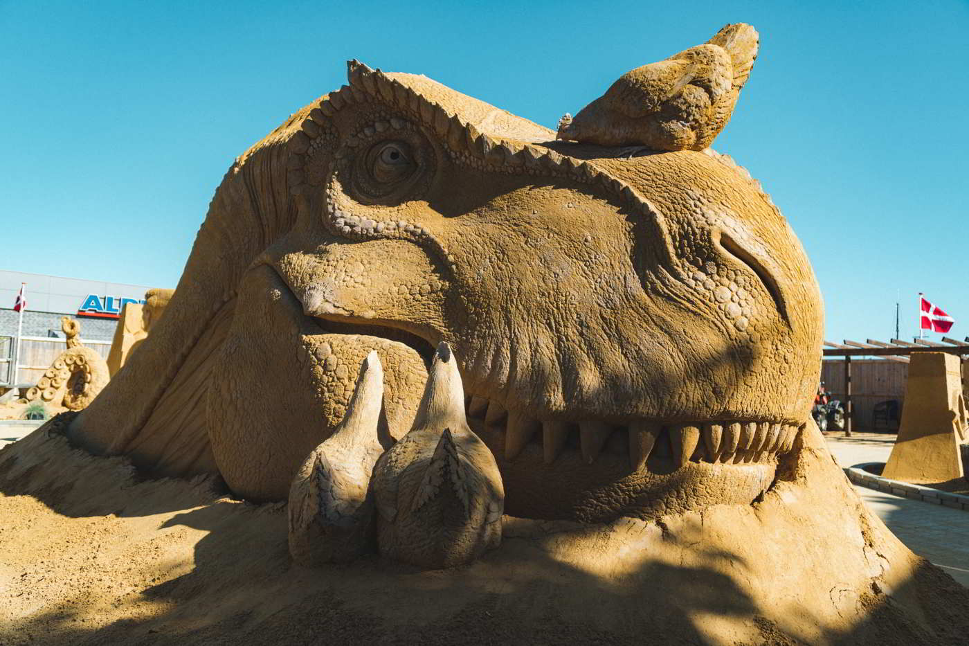 Ein Dinosaurier aus Sand lächelt im Hundested Sandsculpture Park.