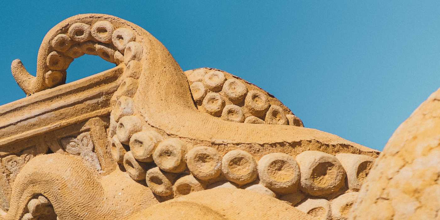 Ein Tintenfisch im Sand streckt seine Tentakel in den Himmel im Hundested Sandskulptur Park.