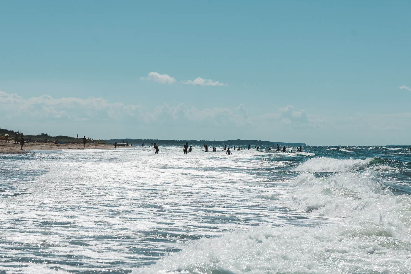 Børn og voksne kaster sig i bølgerne på Tisvildeleje Strand i Nordsjælland
