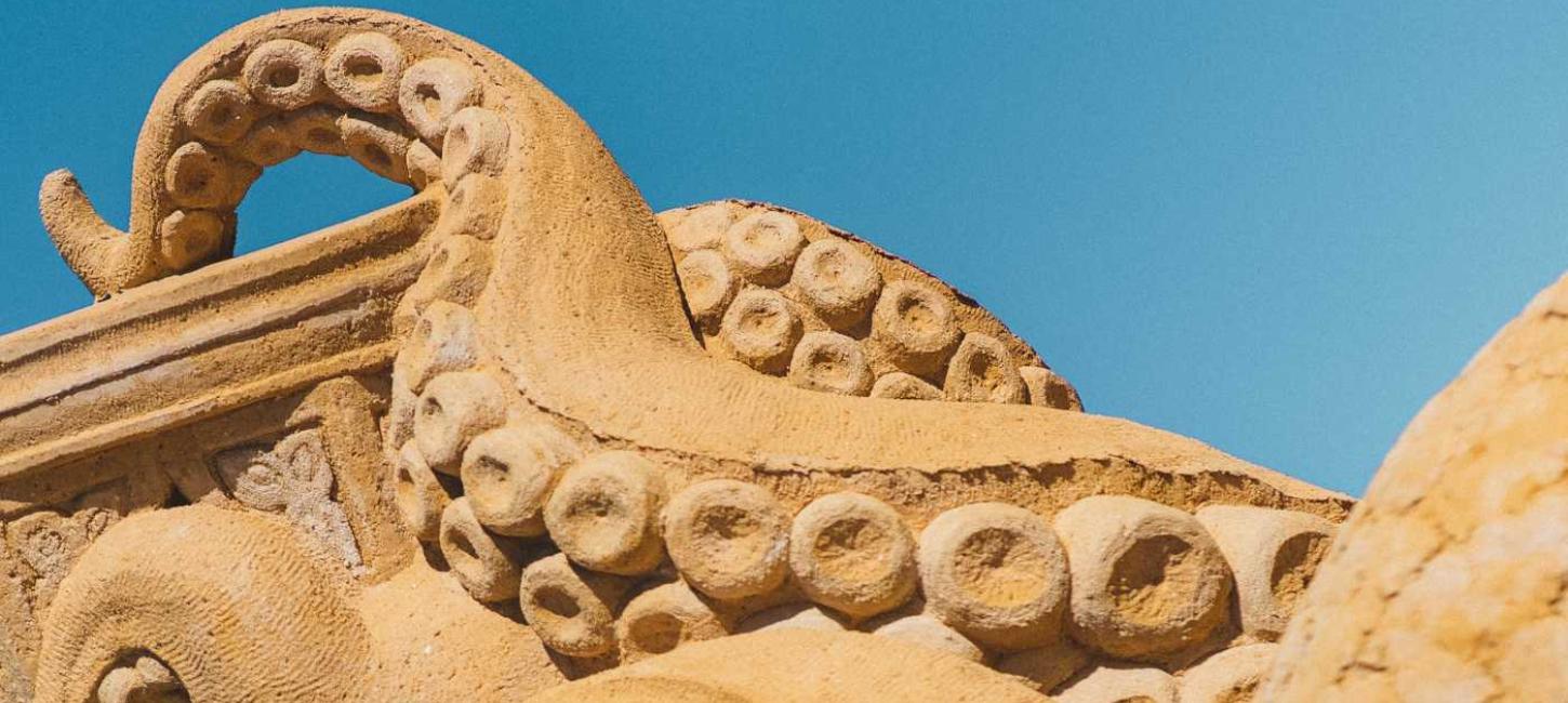 A squid in sand stretches its tentacles towards the sky in Hundested Sand Sculpture Park.