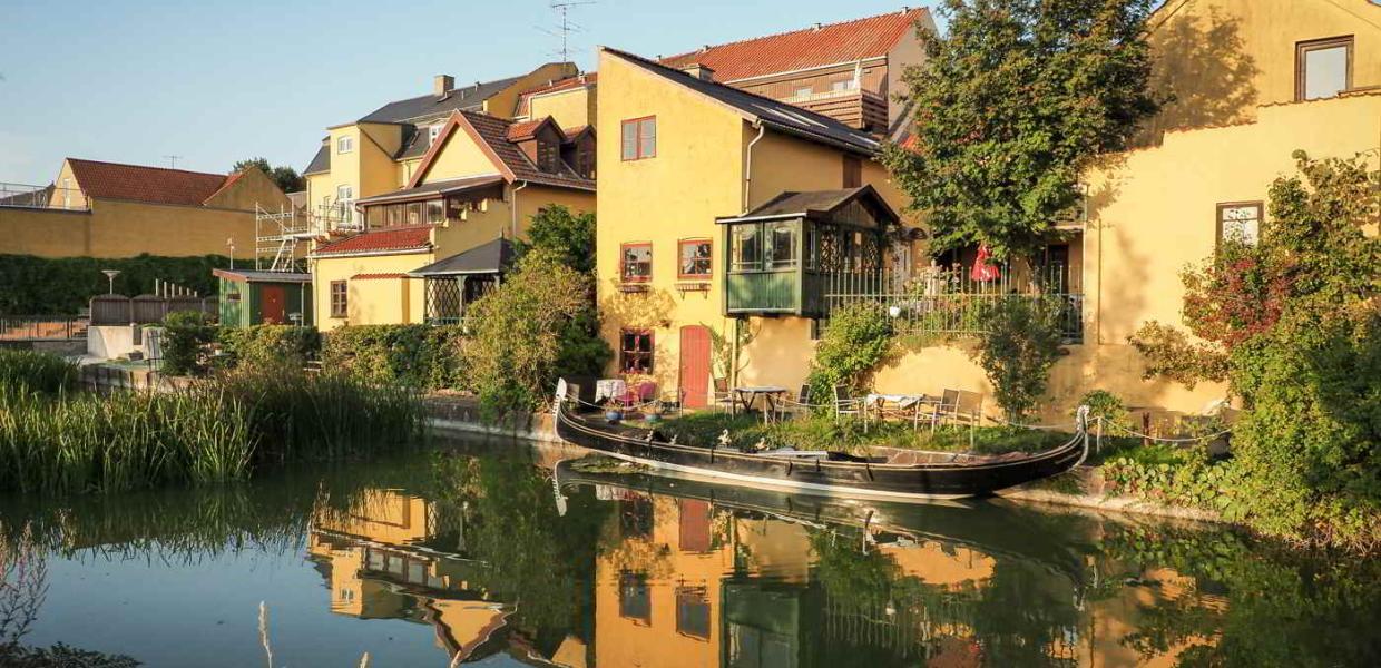 Cozy, yellow buildings bask in the sun on the other side of the canal in Frederiksværk.