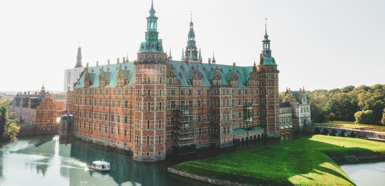 The Little Ferry sails past Frederiksborg Castle in the summer heat in North Zealand, Denmark.