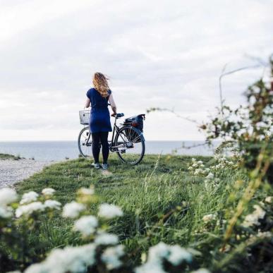 Dame på ved cykel tæt på vandet på Kroneruten