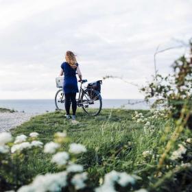 Dame på ved cykel tæt på vandet på Kroneruten