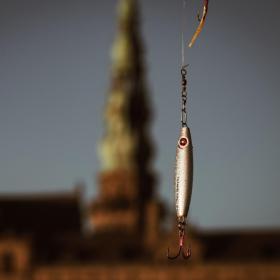 Fiskekrog i sølv holdes i luften foran Kronborg Slot.